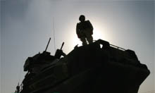 Silhouette of a soldier standing on top of a Tank